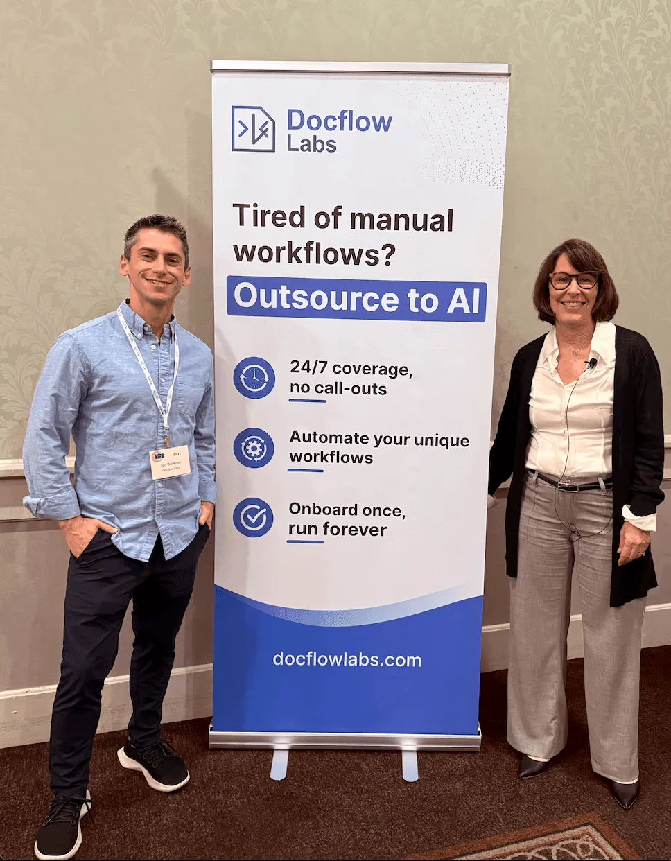 Two people standing next to a banner about outsourcing DME work to AI